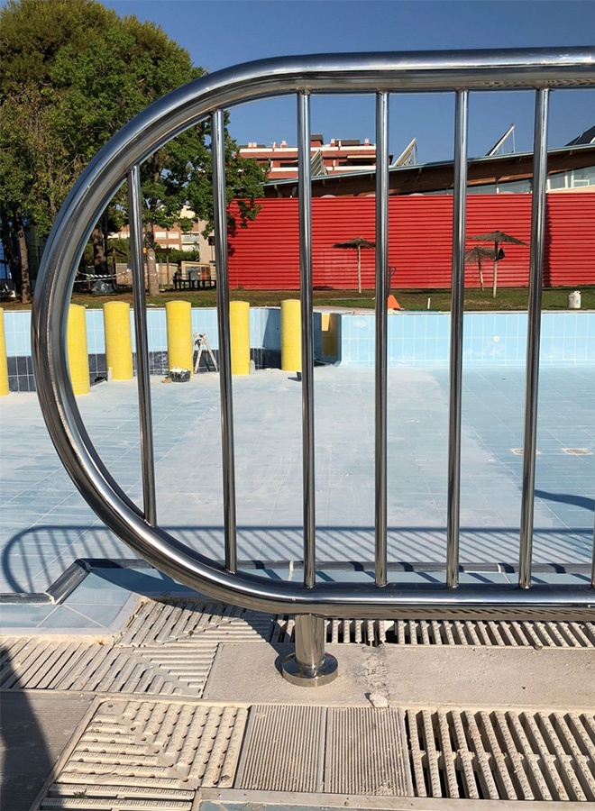 Barandilla de acero inoxidable para piscina municipal en Almassera, con diseño de barrotes verticales y acabada en estilo liso. Hecha a medida para proporcionar seguridad en el entorno acuático.