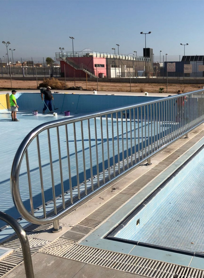 Barandilla de acero inoxidable para piscina municipal en Almassera, con diseño de barrotes verticales y acabada en estilo liso. Hecha a medida para proporcionar seguridad en el entorno acuático.