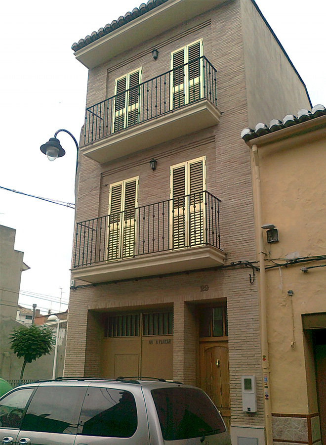 Barandillas de hierro forjado para balcones en dos niveles, con diseño simple de barrotes verticales y detalles decorativos, acabadas en pintura negra y hechas a medida para fachada de ladrillo.